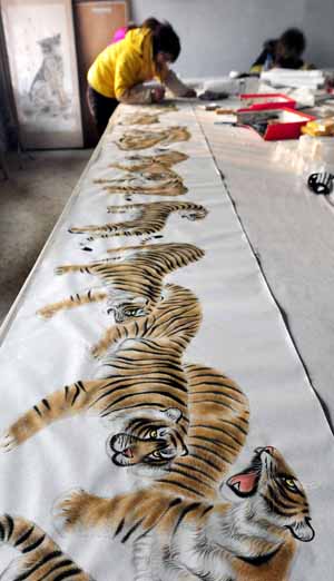 A painter draws a painting of a hundred of tigers in a studio in Wanggongzhuang Village of Minquan County, central China&apos;s Henan Province, Dec. 10, 2009.[Xinhua]