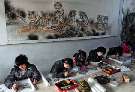 Some students draw tiger paintings in a studio in Wanggongzhuang Village of Minquan County, central China&apos;s Henan Province, Dec. 10, 2009.[Xinhua]
