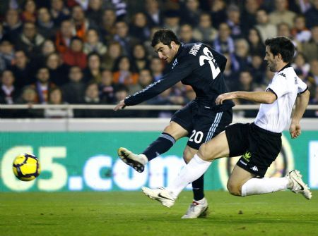 Real Madrid's Gonzalo Higuain (L) shoots to score past Valencia's David Albelda during their Spanish first division soccer match at the Mestalla Stadium in Valencia December 12, 2009. [Xinhua/Reuters]