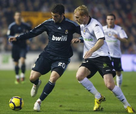 Real Madrid's Gonzalo Higuain (L) and Valencia's Jeremy Mathieu fight for the ball during their Spanish first division soccer match at the Mestalla Stadium in Valencia December 12, 2009. [Xinhua/Reuters]