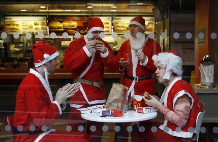 Men wearing Father Christmas outfits eat in a fast food restaurant in central London December 12, 2009. 