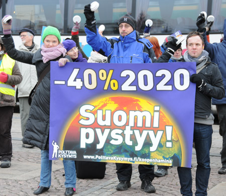 Finnish people hold banners and ring alarms during a protest to demand developed countries&apos; greenhouse gas emission reduction in Helsinki, Dec. 12, 2009.
