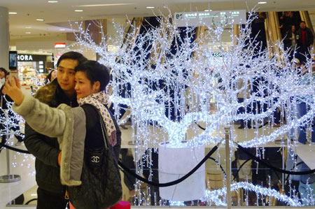 A couple takes photo in front of a decorative tree built for New Year celebration is seen in Shanghai municipality in east China, Dec. 13, 2009.[Pei Xin/Xinhua]