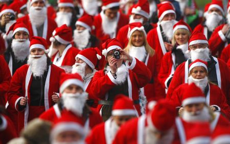 Runners dressed up in Santa Claus outfits jog together during The Great Scottish Santa Run in Princes Street gardens in Edinburgh, Scotland December 13, 2009.[Xinhua/Reuters]