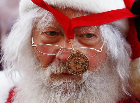 A man dressed up as Santa Claus looks round as his finishing medal gets caught up in his glasses during The Great Scottish Santa Run in Princes Street gardens in Edinburgh, Scotland, December 13, 2009.[Xinhua/Reuters]