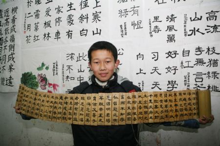 A pupil displays his Chinese calligraphy work on Chinese traditional bamboo slips at the Sunny Future Primary School in Xiangfan, central China&apos;s Hubei Province, Dec. 14, 2009. The school recently launched an activity with the theme of &apos;Getting to Know Chinese Traditional Culture &apos; among pupils. [Gong Bo/Xinhua]