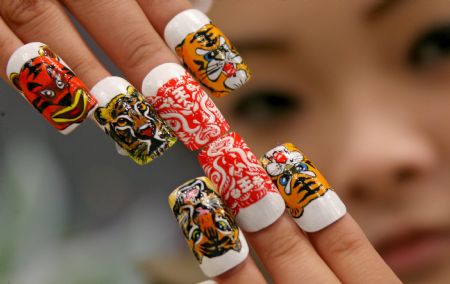 A lady shows a set of false nails with tiger designs at a nail saloon in Yuncheng, north China&apos;s Shanxi province Dec. 13, 2009. The year of 2010 is the year of tiger in Chinese lunar calendar. [Xue Jun/Xinhua]