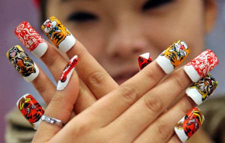 A lady shows a set of false nails with tiger designs at a nail saloon in Yuncheng, north China&apos;s Shanxi province Dec. 13, 2009. The year of 2010 is the year of tiger in Chinese lunar calendar. [Xue Jun/Xinhua]