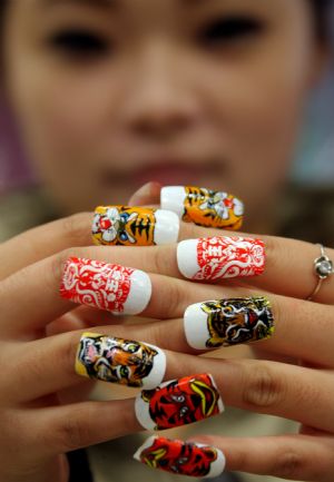 A lady shows a set of false nails with tiger designs at a nail saloon in Yuncheng, north China&apos;s Shanxi province Dec. 13, 2009. The year of 2010 is the year of tiger in Chinese lunar calendar. [Xue Jun/Xinhua]