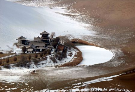 Photo taken on Dec. 14, 2009 shows the snow scene in Yueyaquan Spring (Crescent Spring) near Mingshashan, famouse tourists attractions in Dunhuang of northwest China&apos;s Gansu Province. [Zhang Weixian/Xinhua]