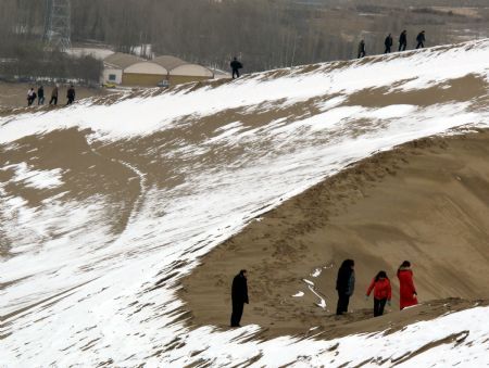 Tourists climb the snow covered Mingshashan in Dunhuang, northwest China&apos;s Gansu Province Dec. 14, 2009. [Zhang Weixian/Xinhua]