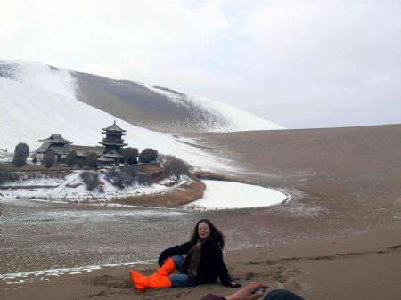 A tourist poses for a photo near the snow covered Mingshashan in Dunhuang, northwest China&apos;s Gansu Province Dec. 14, 2009. [Zhang Weixian/Xinhua] 