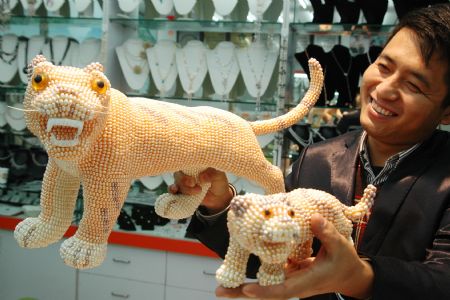 Chinese handicraftsman Ji Xiaoming displays his latest works of Pearl Tiger at his jewelry shop in downtown Suzhou, east China&apos;s Jiangsu Province Dec. 15, 2009. The pearl tigers, which were made of over 10,000 pearls, were two of ten different pearl tigers that Ji Xiaoming had made for the year of 2010, the coming year of the tiger in Chinese lunar calendar. (Xinhua/Zhu Guigen)