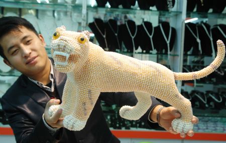 Chinese handicraftsman Ji Xiaoming displays his latest work of Pearl Tiger at his jewelry shop in downtown Suzhou, east China&apos;s Jiangsu Province Dec. 15, 2009. The pearl tiger, which was made of over 10,000 pearls, was one of ten different pearl tigers that Ji Xiaoming had made for the year of 2010, the coming year of the tiger in Chinese lunar calendar. (Xinhua/Zhu Guigen)