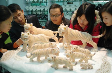 Visitors admire Chinese handicraftsman Ji Xiaoming&apos;s latest works of Pearl Tigers at his jewelry shop in downtown Suzhou, east China&apos;s Jiangsu Province Dec. 15, 2009. The ten pearl tigers were made for the year of 2010, the coming year of the tiger in Chinese lunar calendar. (Xinhua/Zhu Guigen)