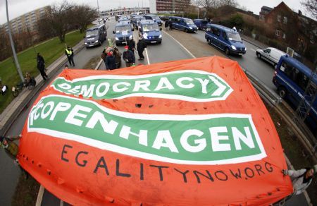 Protestors carry a banner as they march towards Bella Center where the U.N. Climate Change 2009 Conference takes place to disrupt proceedings in Copenhagen December 16, 2009. [Xinhua/Reuters]