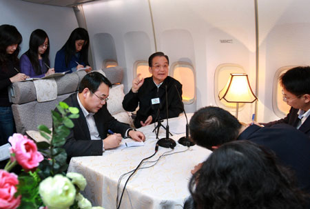 Chinese Premier Wen Jiabao (C) talkes with journalists on the chartered plane to Copenhagen, capital of Denmark , on Dec. 16, 2009. Wen Jiabao arrived at Copenhagen Wednesday evening for the ongoing UN Climate Change Conference. [Xinhua] 