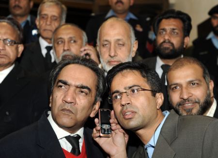 Pakistani lawyers listen to the court decision on a mobile phone outside from the supreme court in Islamabad.[Xinhua/AFP]