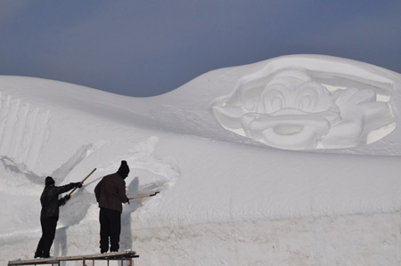 A snow sculptor works on snow carvings at the Jiangxindao Snow Castle in Mudanjiang City of northeast China&apos;s Heilongjiang Province, Dec. 16, 2009. [Xinhua]