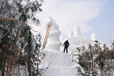 A snow sculptor works on snow carvings at the Jiangxindao Snow Castle in Mudanjiang City of northeast China&apos;s Heilongjiang Province, Dec. 16, 2009. [Xinhua]