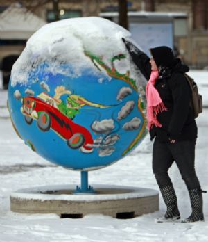 A woman cleans the snow from a globe in Copenhagen December 17, 2009. Copenhagen is the host city for the United Nations Climate Change Conference 2009, which lasts from December 7 until December 18.
