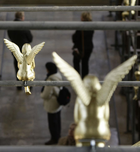 Church visitors stand under 300 golden angels attached to scaffolding during an exhibition in the Holy Cross church in Munich December 17, 2009. The installation known as &apos;Guardian angel over Munich&apos; by German artist Ottmar Hoerl runs until February 2, 2010. 