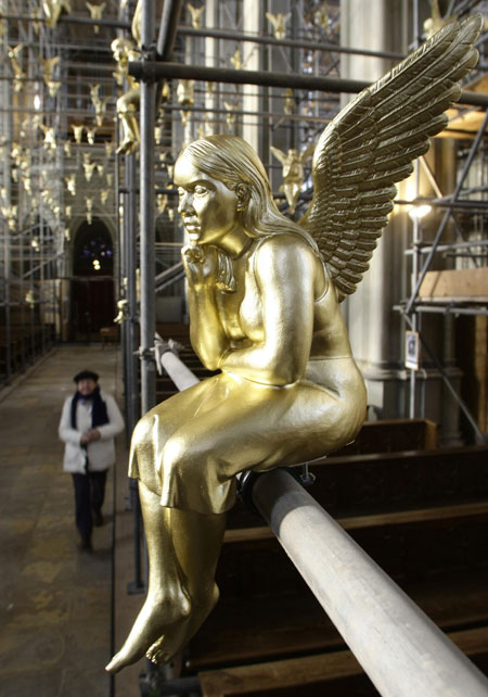 A church visitor passes 300 golden angels attached at scaffolding during an exhibition in the Holy Cross church in Munich December 17, 2009. The installation known as &apos;Guardian angel over Munich&apos; by German artist Ottmar Hoerl runs until February 2, 2010. 