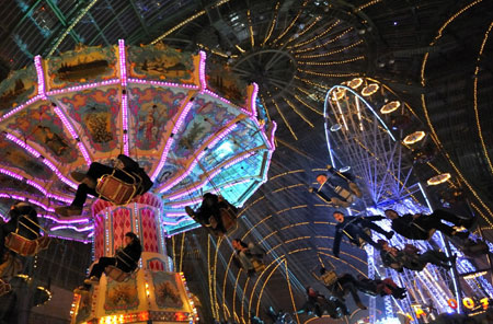 People sit in a merry-go-round at a funfair inside Paris&apos; Grand Palais as part of holiday activities in the French capital December 17, 2009. The fair opens on December 18 and will run until January 1.