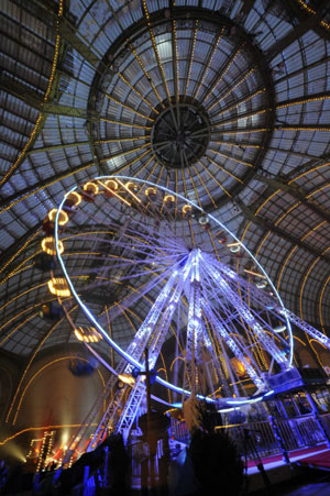 People walk near a giant ferris wheel inside Paris&apos; Grand Palais as part of holiday activities in the French capital December 17, 2009. 