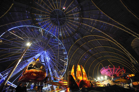 Children sit in the helicopter of a merry-go-round at a funfair inside Paris&apos; Grand Palais as part of holiday activities in the French capital December 17, 2009. The fair opens on December 18 and will run until January 1.