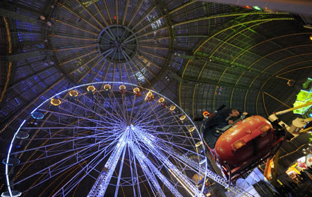 A child sits in the helicopter of a merry-go-round at a funfair set inside Paris&apos; Grand Palais as part of holiday activities in the French capital December 17, 2009. The fair opens on December 18 and will run untill January 1.