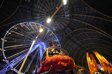 Children sit in the helicopter of a merry-go-round at a funfair inside Paris' Grand Palais as part of holiday activities in the French capital December 17, 2009.