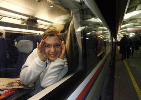 A passenger reacts to the camera as she looks out of a window aboard the Sapsan high speed train in Moscow, December 17, 2009. Sapsan will take passengers from Moscow to St. Petersburg in 3 hours and 45 minutes at a top speed of 250 kmph (155 miles per hour). 