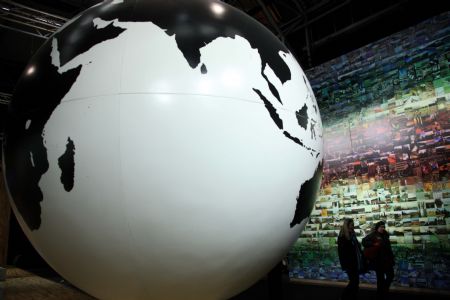 Two women are seen beside a globe model at the empty hall of the Bella Center during the United Nations Climate Change Conference in Copenhagen, capital of Denmark, Dec. 19, 2009. 