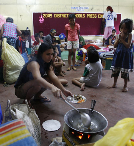 An evacuee cooks food inside a classroom turned into a makeshift evacuation centre for residents living at the slopes of the Mayon Volcano in Legaspi city, about 500 km (310 miles) south of Manila December 21, 2009. The Philippines raised the alert level around the country&apos;s most active volcano on Sunday, warning of a possible hazardous eruption within days and extending a &apos;no-go zone&apos; up to 10 km (6 miles). [Xinhua/Reuters]