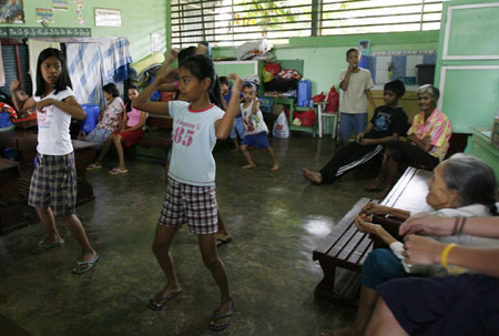 Mayon Volcano evacuees practise dancing for their Christmas party at a temporary shelter for residents living at the slopes of the volcano in Legaspi city, about 500 km (310 miles) south of Manila December 21, 2009. The Philippines raised the alert level around the country&apos;s most active volcano on Sunday, warning of a possible hazardous eruption within days and extending a &apos;no-go zone&apos; up to 10 km (6 miles). [Xinhua/Reuters]