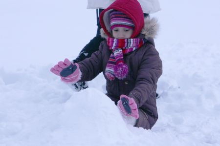 A girl plays with snow in a park in New York City, the U.S., Dec. 20, 2009.(Xinhua/Wang Chengyun)