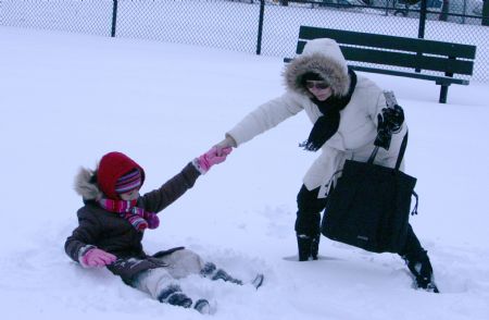 A girl plays with her mother in snow in a park in New York City, the U.S., Dec. 20, 2009.(Xinhua/Wang Chengyun)