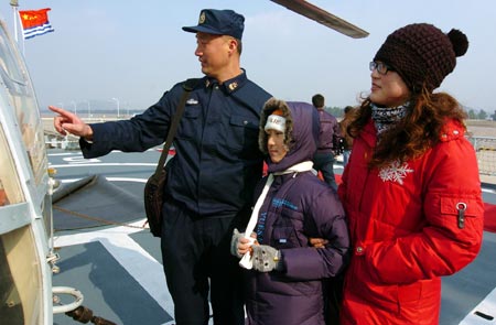 A Chinese navy soldier gives an introduction on the "Zhoushan" Warship to his wife and daughter during their visit to the warship in a military port in Zhoushan, Zhejiang Province, Dec. 20, 2009. (Xinhua/Guo Gang)