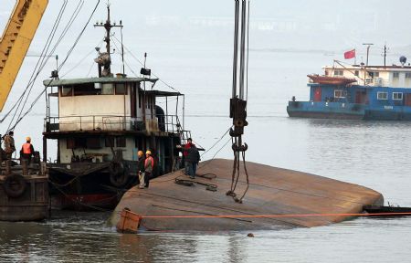 Rescuers salvage a capsized sand carrier vessel on Jingkou section of the Yangtze River, in Jiangxia District of Wuhan, central China&apos;s Hubei Province, Dec. 20, 2009. The sand carrier vessel collided with a 1,000-ton freight vessel at around 4:00 a.m. and sunk. Three shipmen escaped and no casualties were caused.(Xinhua Photo)