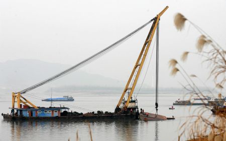 Rescuers salvage a capsized sand carrier vessel on Jingkou section of the Yangtze River, in Jiangxia District of Wuhan, central China&apos;s Hubei Province, Dec. 20, 2009.(Xinhua Photo)