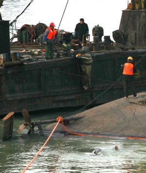 Rescuers salvage a capsized sand carrier vessel on Jingkou section of the Yangtze River, in Jiangxia District of Wuhan, central China&apos;s Hubei Province, Dec. 20, 2009.(Xinhua Photo)