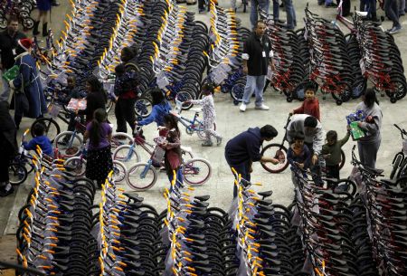 An L.A. Dream Center volunteer helps a boy choose his new bike at the LA Sports Arena in Los Angeles, California, December 20, 2009. Thousands of bicycles and toys were given away to families in need during The Dream Center Christmas in the City event.