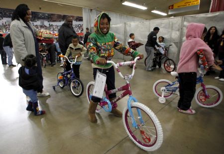 Nine-year-old Precious Robinson smiles while riding her new bicycle as her family leaves the L.A. Sports Arena in Los Angeles, California, December 20, 2009. Thousands of bicycles and toys were given away to families in need during The Dream Center Christmas in the City event.