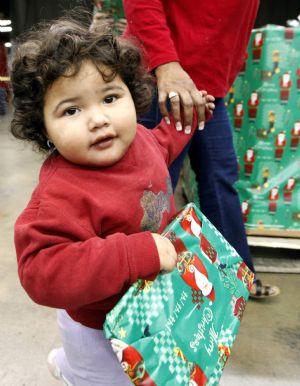 Eighteen-month-old Ashley Velazquez holds her new wrapped toy in the LA Sports Arena in Los Angeles, California, December 20, 2009. Thousands of bicycles and toys were given away to families in need during The Dream Center Christmas in the City event. 