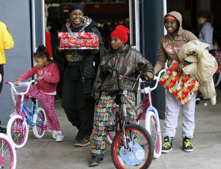 Jennifer Browne (2nd L) carries toys as her five-year-old niece Amani Middlebrooks (L), her 10-year-old son Semajay Jackson (3rd L) and her 11-year-old relative Kayjjahnae Simmons walk out with new bicycles at the LA Sports Arena in Los Angeles, California, December 20, 2009. Thousands of bicycles and toys were given away to families in need during The Dream Center Christmas in the City event. Browne and her family waited in line for 27 hours, including staying overnight, to ensure that they were one of the families to receive the gifts. 