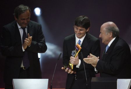 UEFA President Michel Platini (L) and FIFA President Sepp Blatter (R) applaud Lionel Messi of Argentina as he holds his trophy of the FIFA Men's World Player of the Year 2009 soccer award during a ceremony in Zurich December 21, 2009.  Lionel Messi became the first Argentine to win the FIFA World Player of the Year award on Monday.