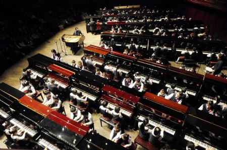 Chinese pianist Lang Lang plays a unison with 100 children as he visits Shenzhen in south China&apos;s Guangdong Province on Dec. 21, 2009.