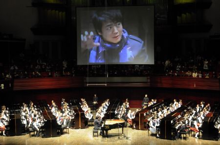 Chinese pianist Lang Lang plays a unison with 100 children as he visits Shenzhen in south China&apos;s Guangdong Province on Dec. 21, 2009. 