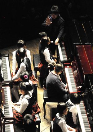 Chinese pianist Lang Lang tutors a girl as he visits Shenzhen in south China&apos;s Guangdong Province on Dec. 21, 2009. Lang Lang played a unison with 100 children in the city.